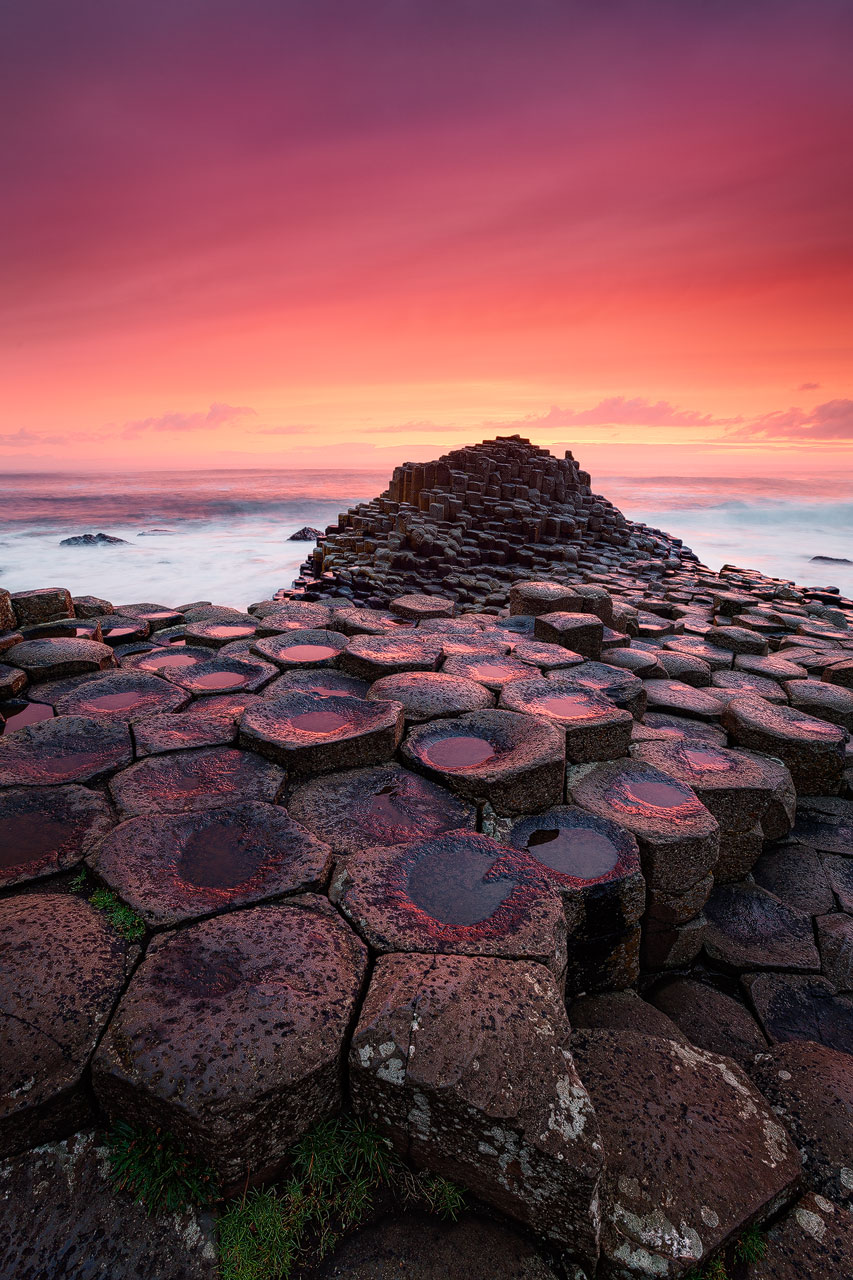 The hexagonal rocks of the Giants Causeway in Northern Ireland under a blood red sky.